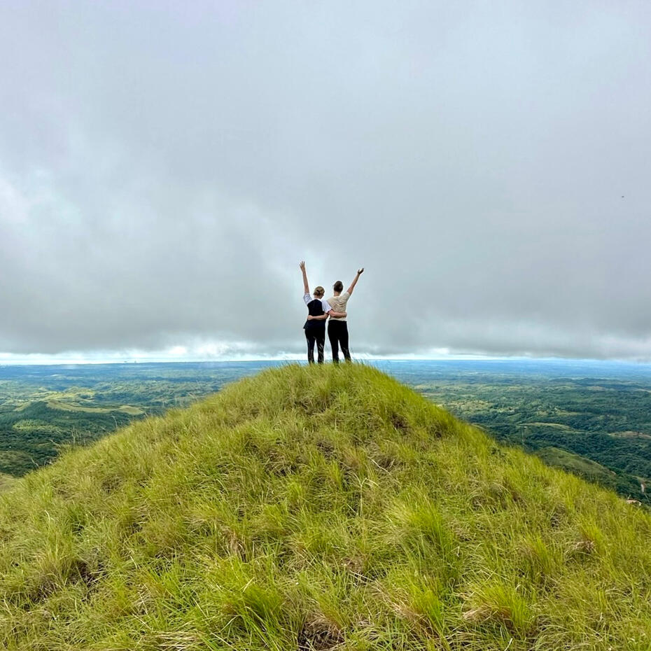 Two women standing on a mountain, cheering each other up.
